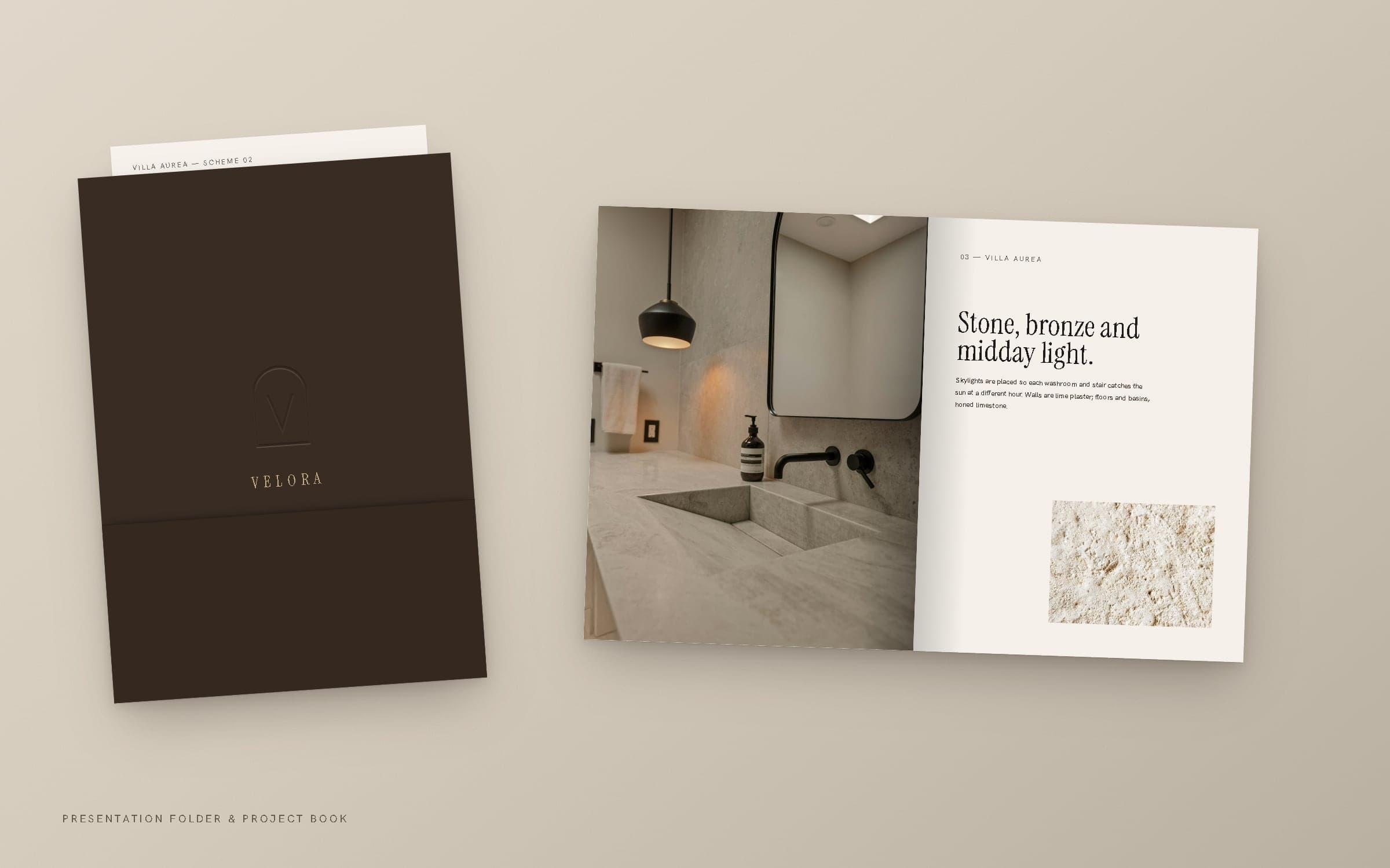 Umber presentation folder with a debossed monogram beside an open VELORA project book.